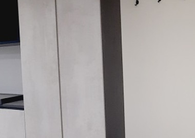 玄關聯結客廳電視牆的一側，規劃汙衣區與穿鞋椅。