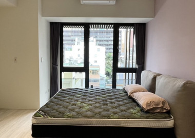 主臥以木地板和白牆基底搭配床頭油漆跳色，營造簡約無壓力的睡眠環境。