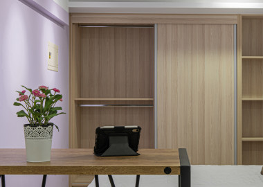 以粉紫跳色牆和木質收納櫃打造溫馨臥室空間。