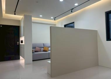 客廳電視牆同時界定餐廳位置，不做到頂保留採光與通風。