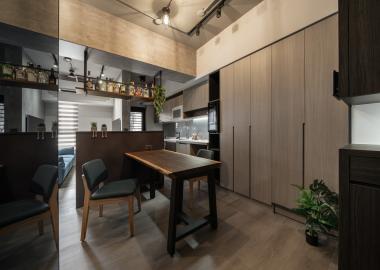 餐廳作為居家核心連結廚房與客廳，樑下吊櫃收納屋主的酒品。
